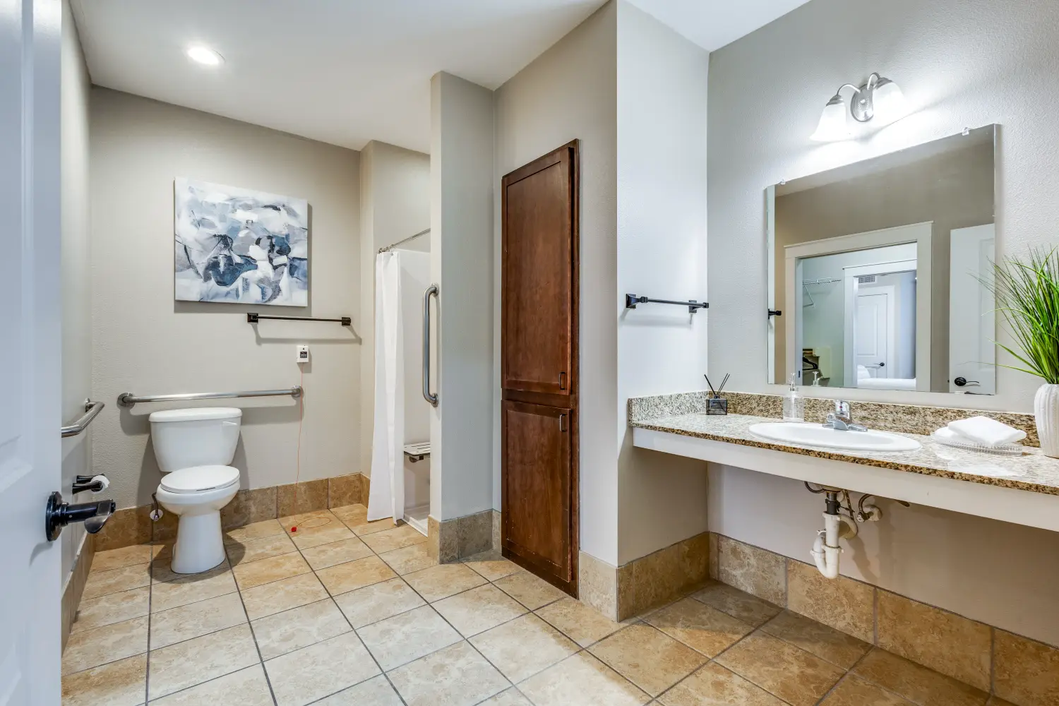 Accessible senior living apartment bathroom with walk in shower vanity and safety rails at The Ivy of McKinney Texas