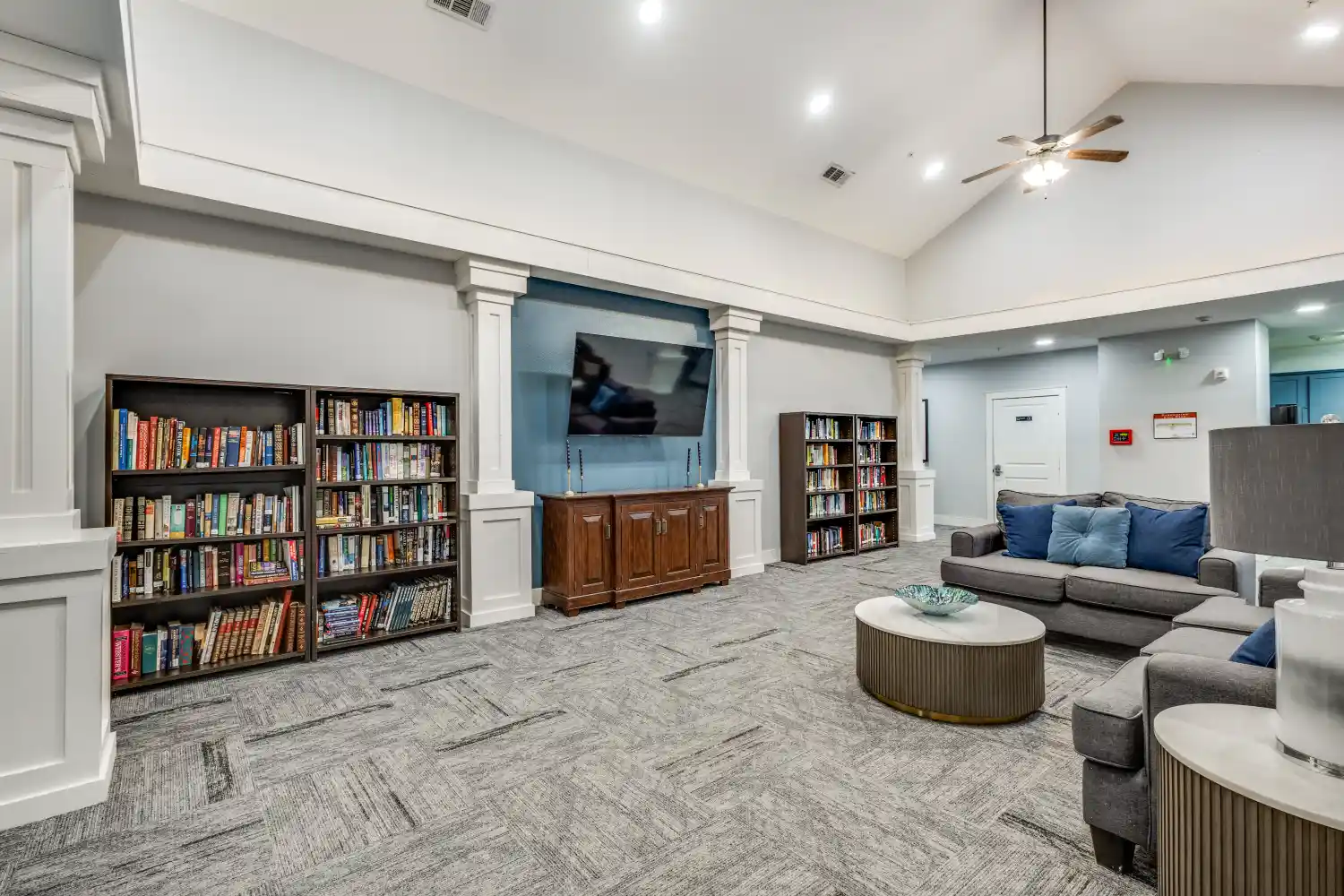 Senior living community library lounge with bookshelves seating and television at The Ivy of McKinney assisted living Texas